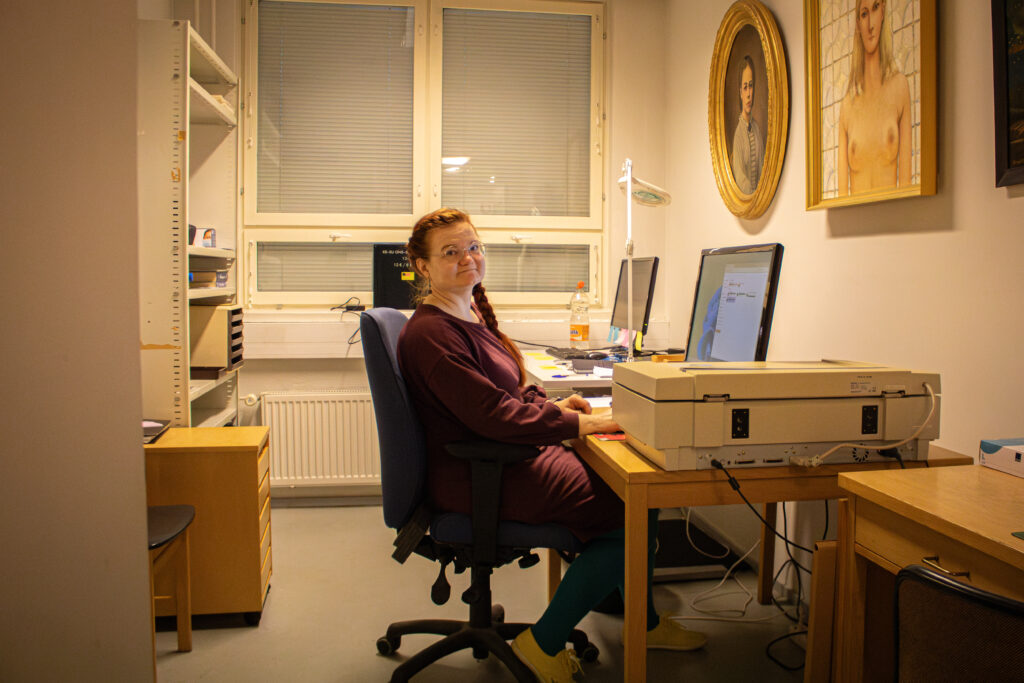 Mannerkoski istuu tietokoneen äärellä ja hymyilee kohti kameraa.