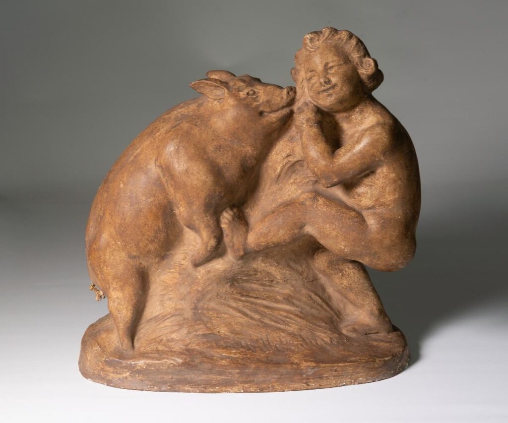 Statyett i färgad gips föreställande gosse lekande med en gris.