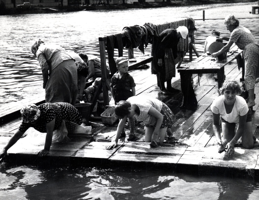 Ihmisiä pesemässä mattoja mattolaiturilla.