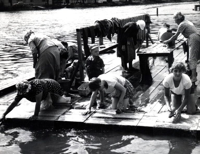 Ihmisiä pesemässä mattoja mattolaiturilla.