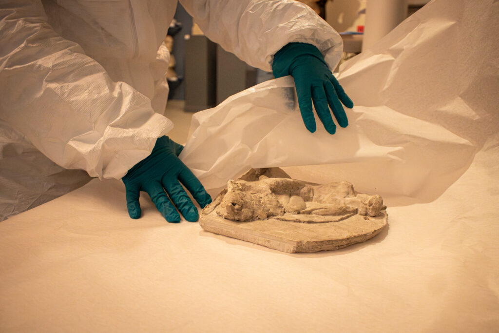 Lähikuvaa veistoksen pakkaamisesta valkoiseen silkkipaperiin.